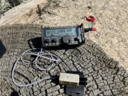 The Elecraft KX2 deployed on a stump out at Silver Saddle Ranch. On the right side of the radio is a BNC/binding post adapter. Connected to the red post is the radiating element, about 25-ft of wire affixed to a 10-m SOTAbeams telescopic mast. Connected to the black post is another wire, about 25-ft long (or so) thrown on the ground to be the counterpoise.