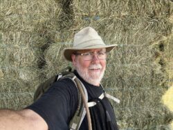 This is an iPhone selfie of me with the Osprey Stratos daypack in front of the Silver Saddle Ranch alfalfa haystack.